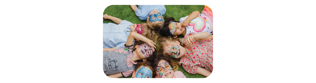 Group of children lying in a circle on the floor, smiling and looking up at the camera, symbolizing happiness, connection, and emotional wellbeing.